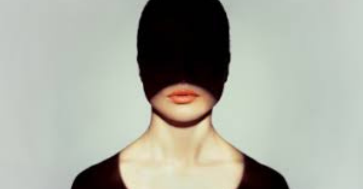 Woman in front of white backdrop with a shadow cast over her face shadow IT
